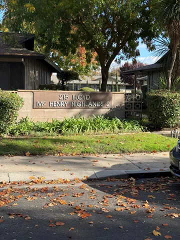 a view of a street with a bench under large trees