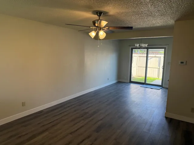 an empty room with wooden floor closet and windows