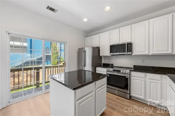 a kitchen with stainless steel appliances granite countertop a stove a sink and a microwave
