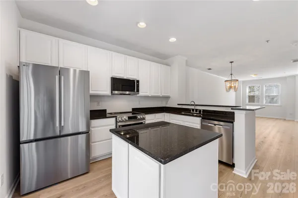 a kitchen view with stainless steel appliances granite countertop a refrigerator a sink a stove a microwave and island