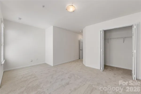 an empty room with closet and a chandelier fan
