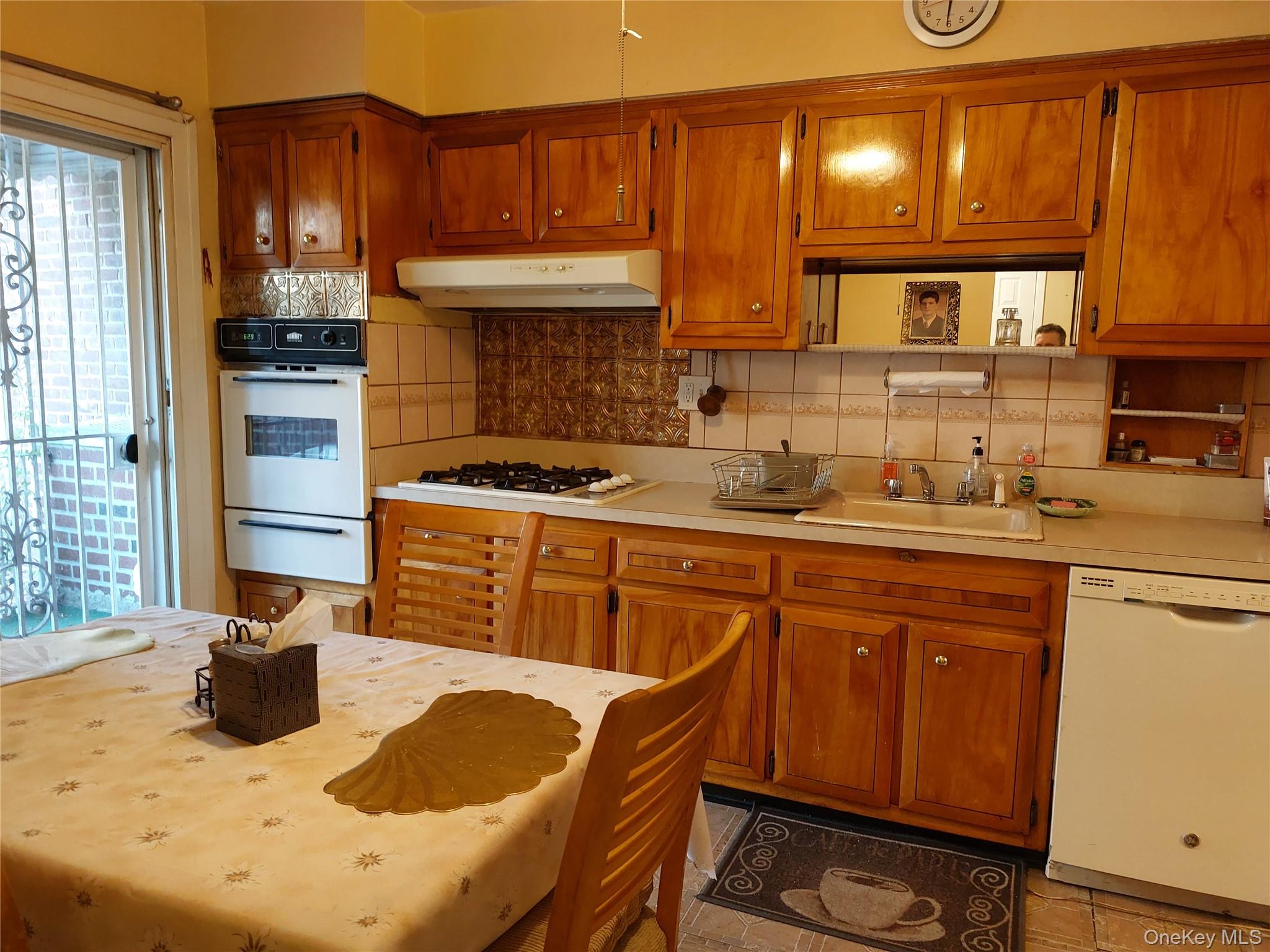 108-19 48th Avenue Queens, NY 11368 - Photo 3 of 21 Kitchen with backsplash, light countertops, white appliances, brown cabinets, and a warming drawer