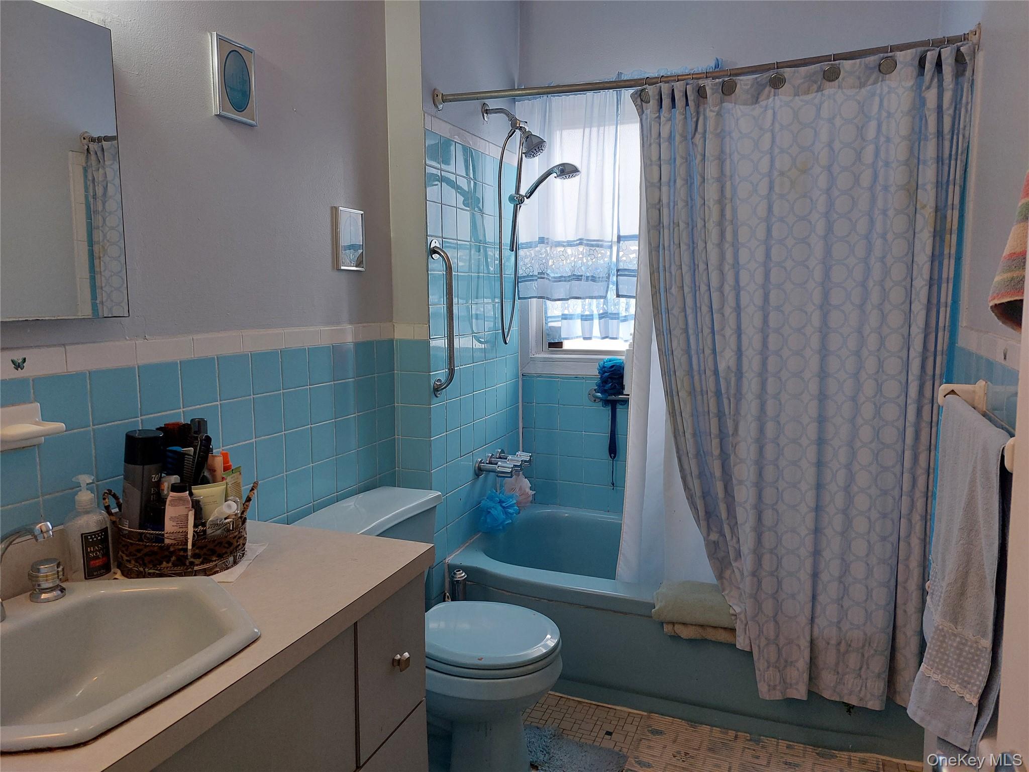 108-19 48th Avenue Queens, NY 11368 - Photo 10 of 21 Bathroom with shower / bath combination with curtain, tile walls, vanity, wainscoting, and tile patterned flooring
