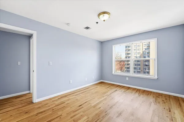 an empty room with wooden floor and windows