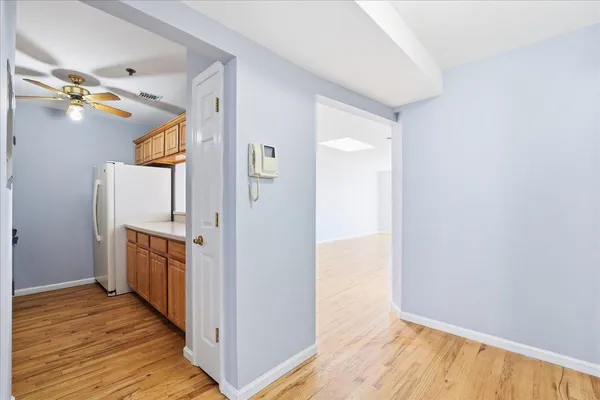 a view of hallway with wooden floor and cabinet