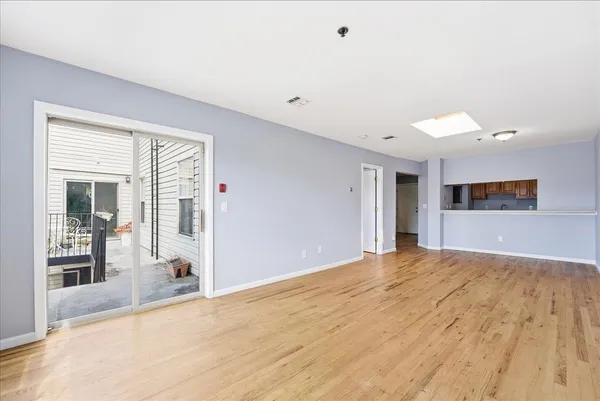 a view of an empty room with wooden floor and a window