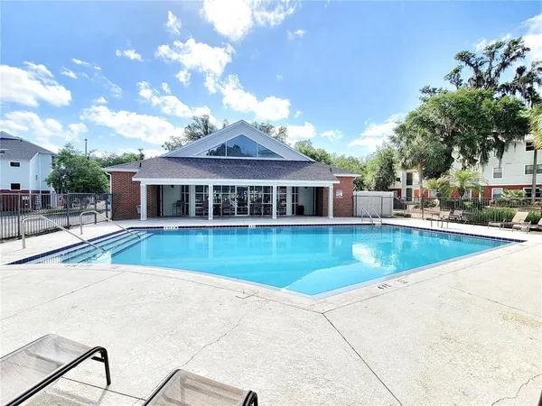 a view of pool with a lawn chairs under an umbrella
