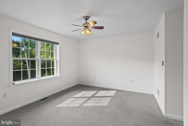 an empty room with a window and a chandelier fan