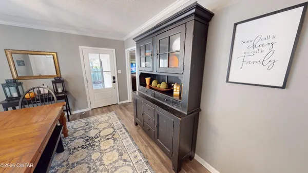 a view of a hallway to room with wooden floor and furniture