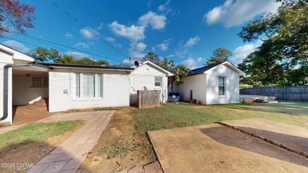a view of a house with a yard and large tree