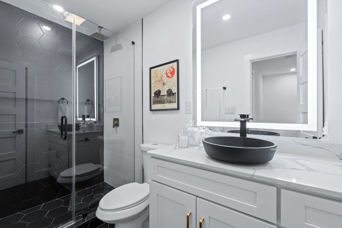 2706 Wheless Lane, Unit BLDG 5 Austin, TX 78723 - Photo 7 of 12 a bathroom with a granite countertop sink a toilet a shower and a mirror