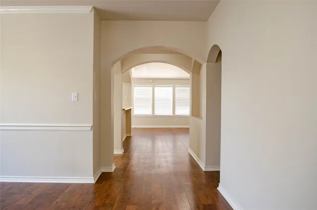 a view of a hallway with wooden floor and a window
