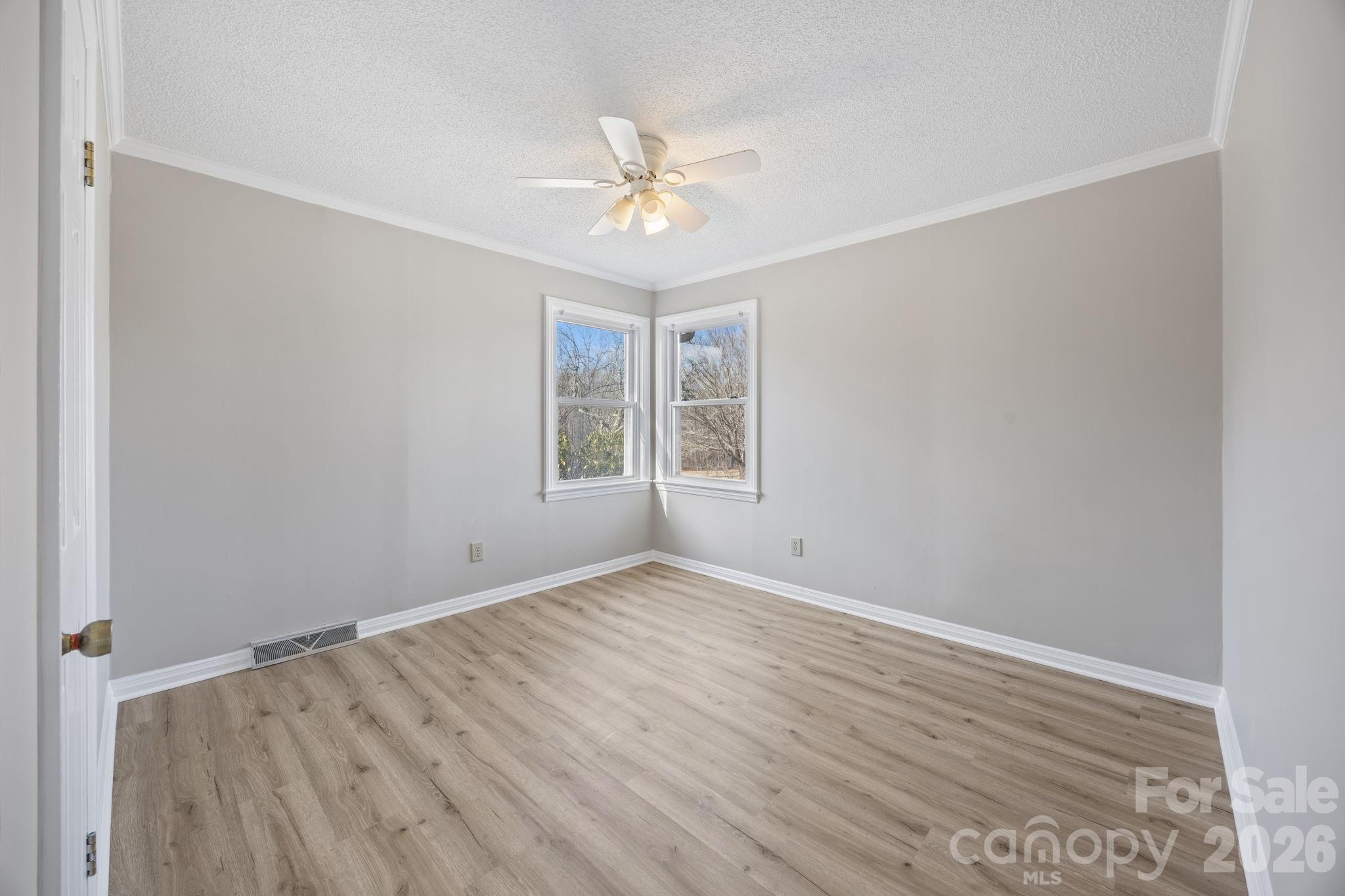 33633 Mann Road Albemarle, NC 28001 - Photo 29 of 39 an empty room with wooden floor chandelier fan and windows