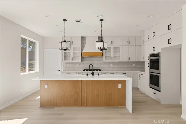 a view of a kitchen with kitchen island a sink stainless steel appliances and cabinets