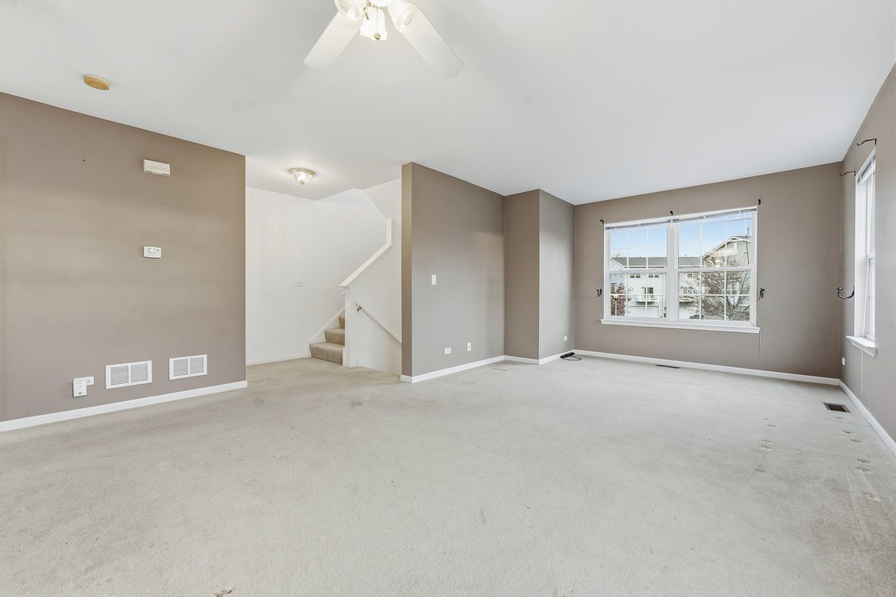 335 Holiday Lane Round Lake, IL 60073 - Photo 3 of 25 an empty room with windows and chandelier fan