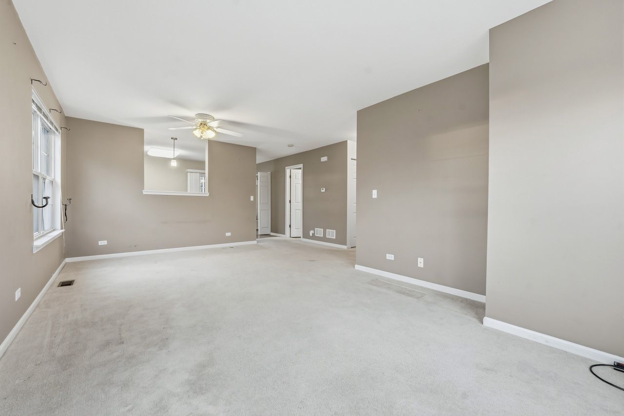 335 Holiday Lane Round Lake, IL 60073 - Photo 4 of 25 an empty room with windows and chandelier fan