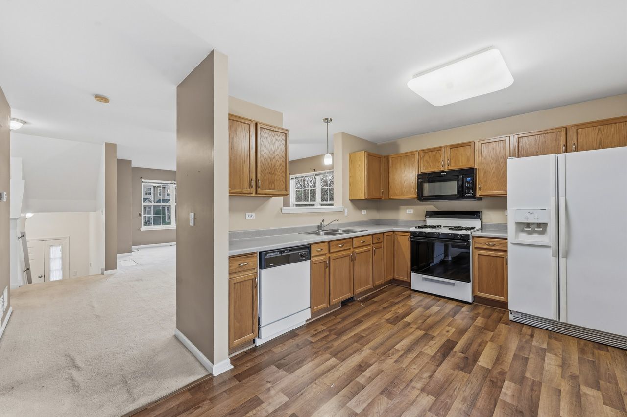 335 Holiday Lane Round Lake, IL 60073 - Photo 6 of 25 a large kitchen with cabinets wooden floor and stainless steel appliances