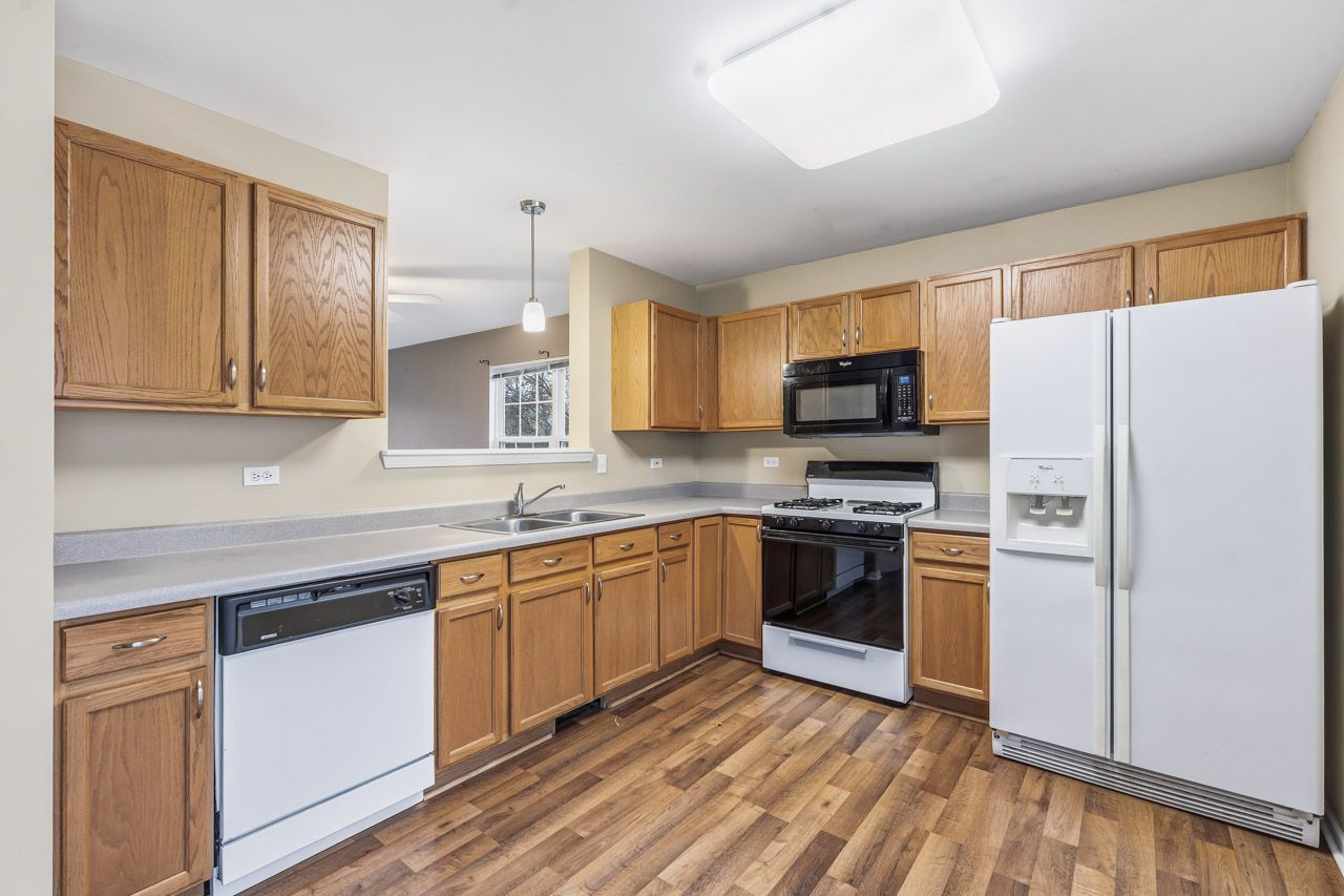 335 Holiday Lane Round Lake, IL 60073 - Photo 7 of 25 a kitchen with stainless steel appliances granite countertop a refrigerator stove a sink and dishwasher with wooden floor