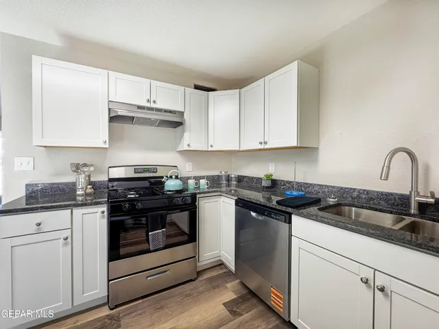 a kitchen with granite countertop white cabinets sink and stainless steel appliances