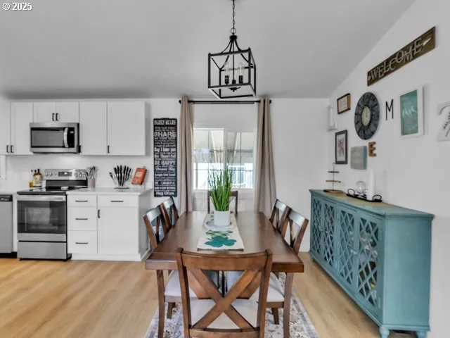 a kitchen with stainless steel appliances granite countertop a stove top oven a sink a dining table and chairs with wooden floor