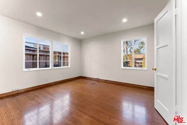 a view of an empty room with window and wooden floor