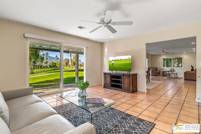 a living room with stainless steel appliances furniture a rug and a window