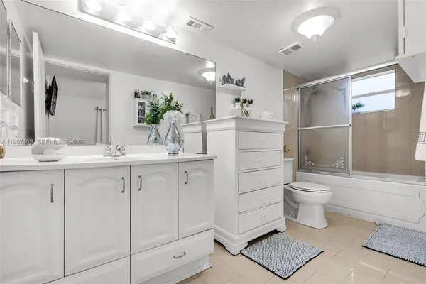 a bathroom with a double vanity sink a toilet and a shower
