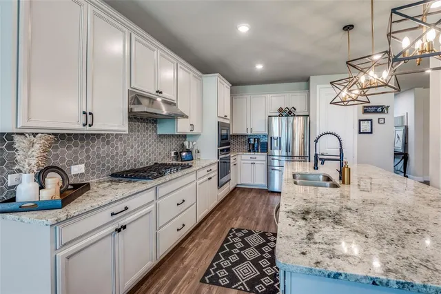 a large kitchen with stainless steel appliances granite countertop a sink a stove and cabinets