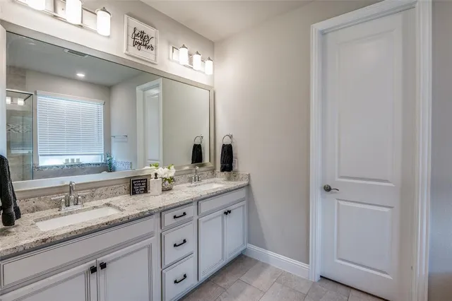 a bathroom with a granite countertop double vanity sink and a mirror