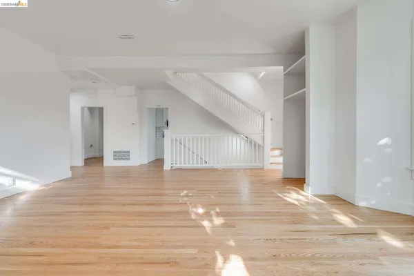 a view of a livingroom with wooden floor and staircase