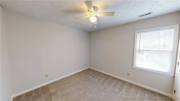 an empty room with a window and a fan