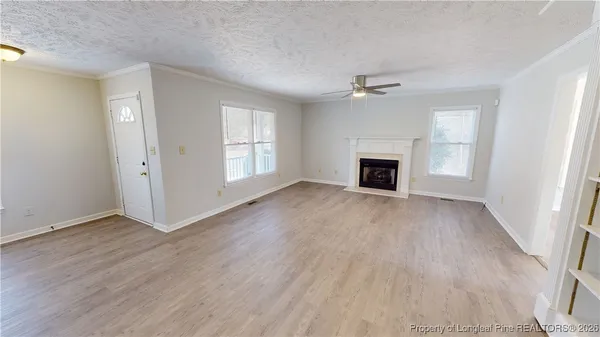 an empty room with windows fireplace and wooden floor