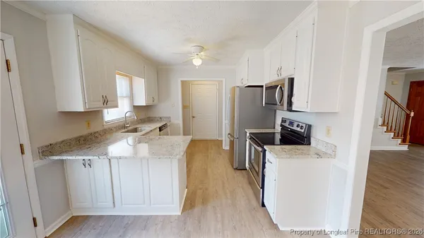 a kitchen with kitchen island a counter top space a sink stainless steel appliances and cabinets