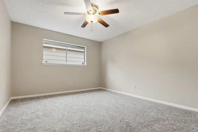 an empty room with a window and a fan