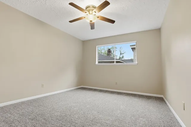 an empty room with a window and a fan