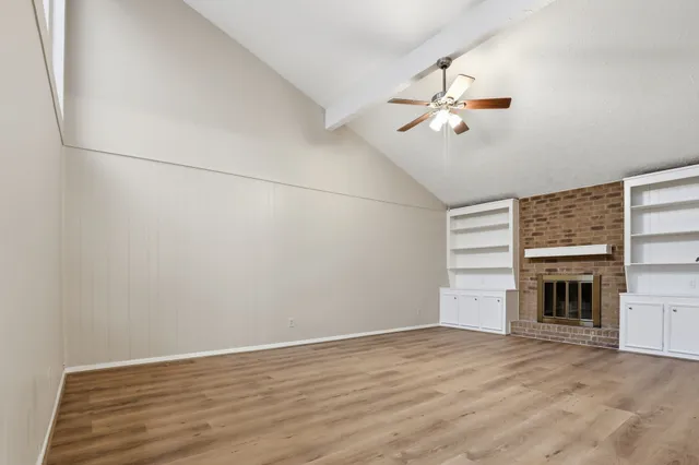 an empty room with windows and fireplace