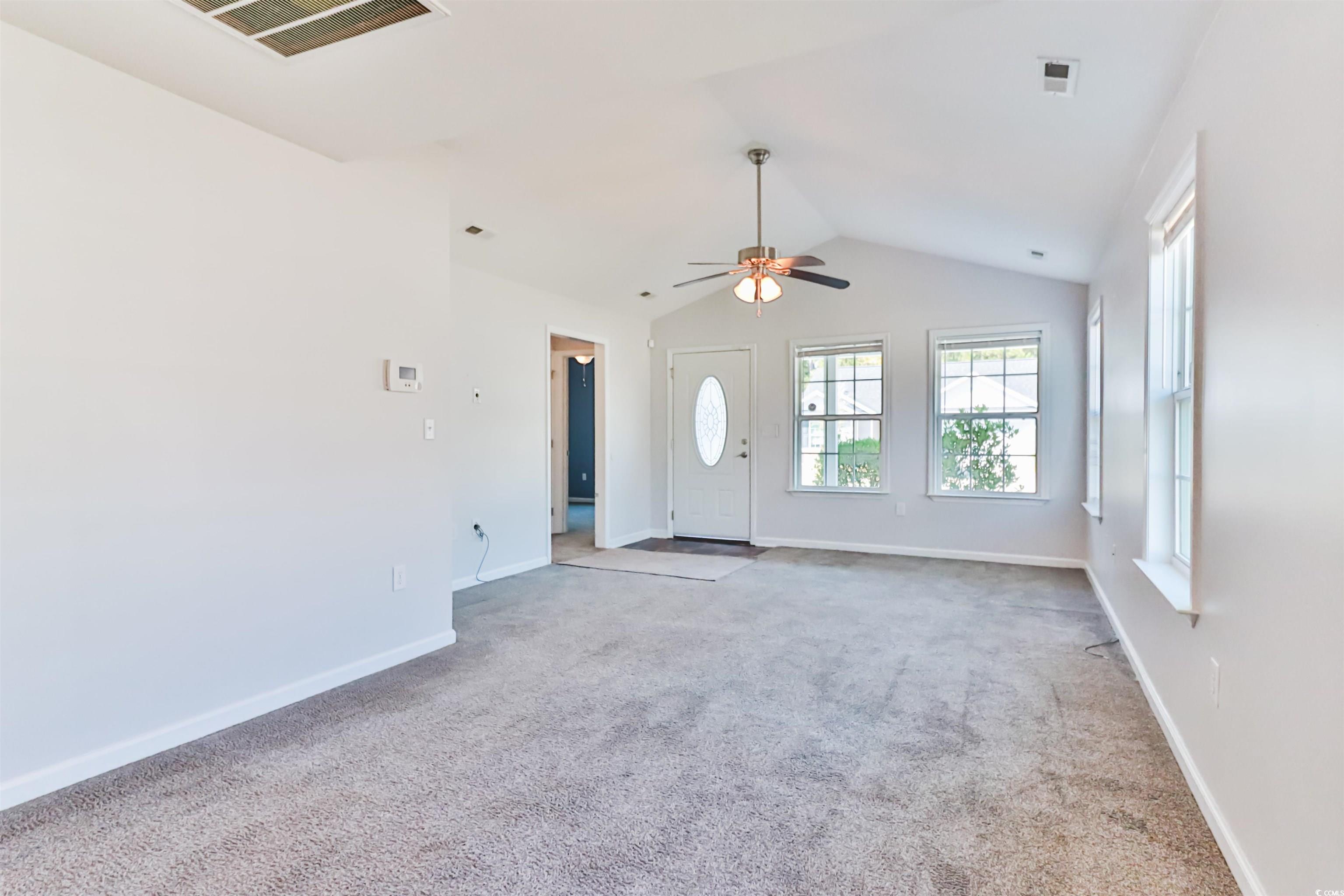 Unfurnished living room with ceiling fan, vaulted
