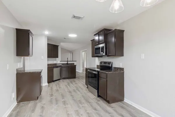 a kitchen with stainless steel appliances a stove top oven a sink dishwasher a refrigerator and a microwave