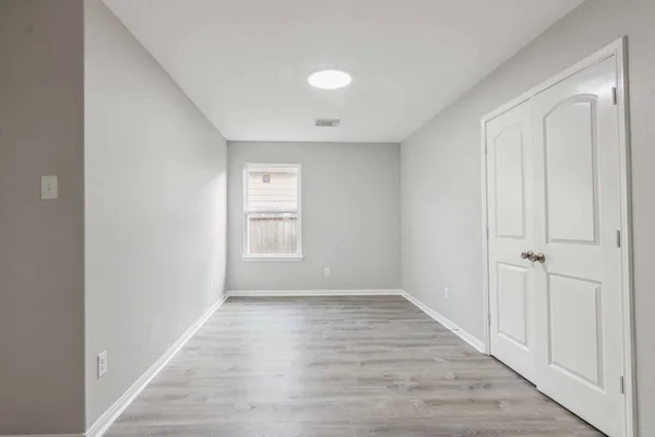 a view of an empty room with wooden floor and a window