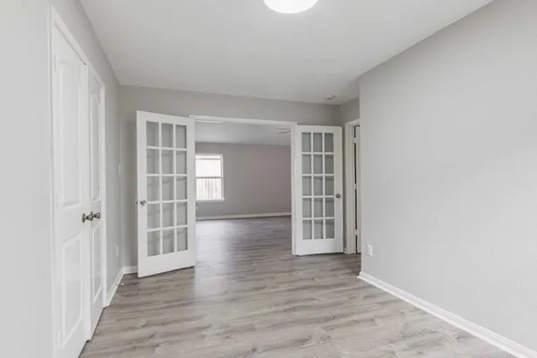 an empty room with wooden floor and windows