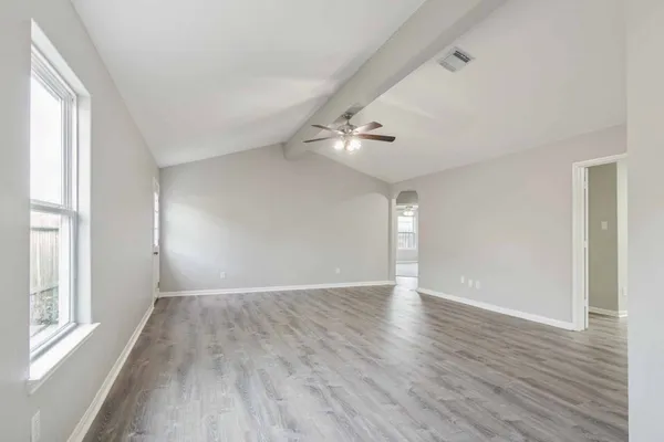 a view of an empty room with wooden floor and a window