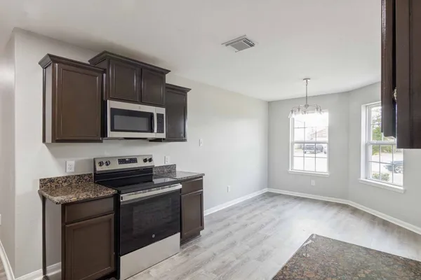a kitchen with granite countertop a sink stove and microwave