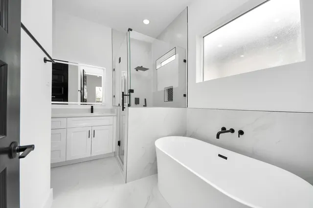 a bathroom with a bathtub a sink a mirror and a shower