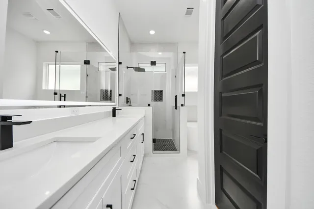 a large white bathroom with a double vanity sink a mirror and a shower