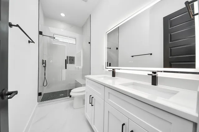 a bathroom with a sink toilet double vanity and shower