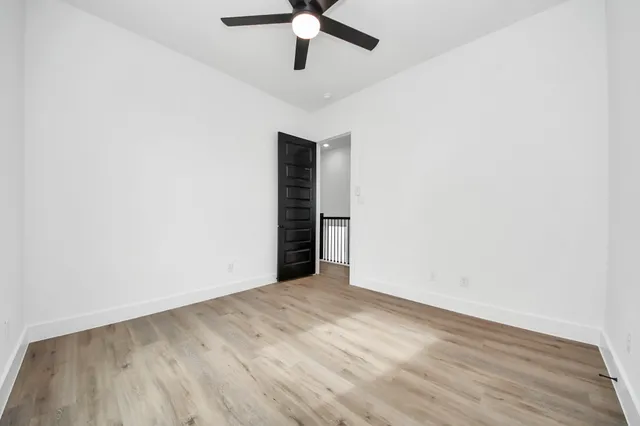 an empty room with wooden floor ceiling fan and window