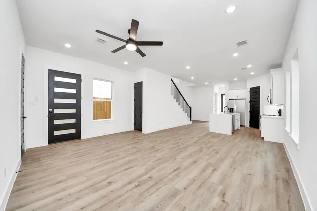 a view of an empty room with a window and wooden floor