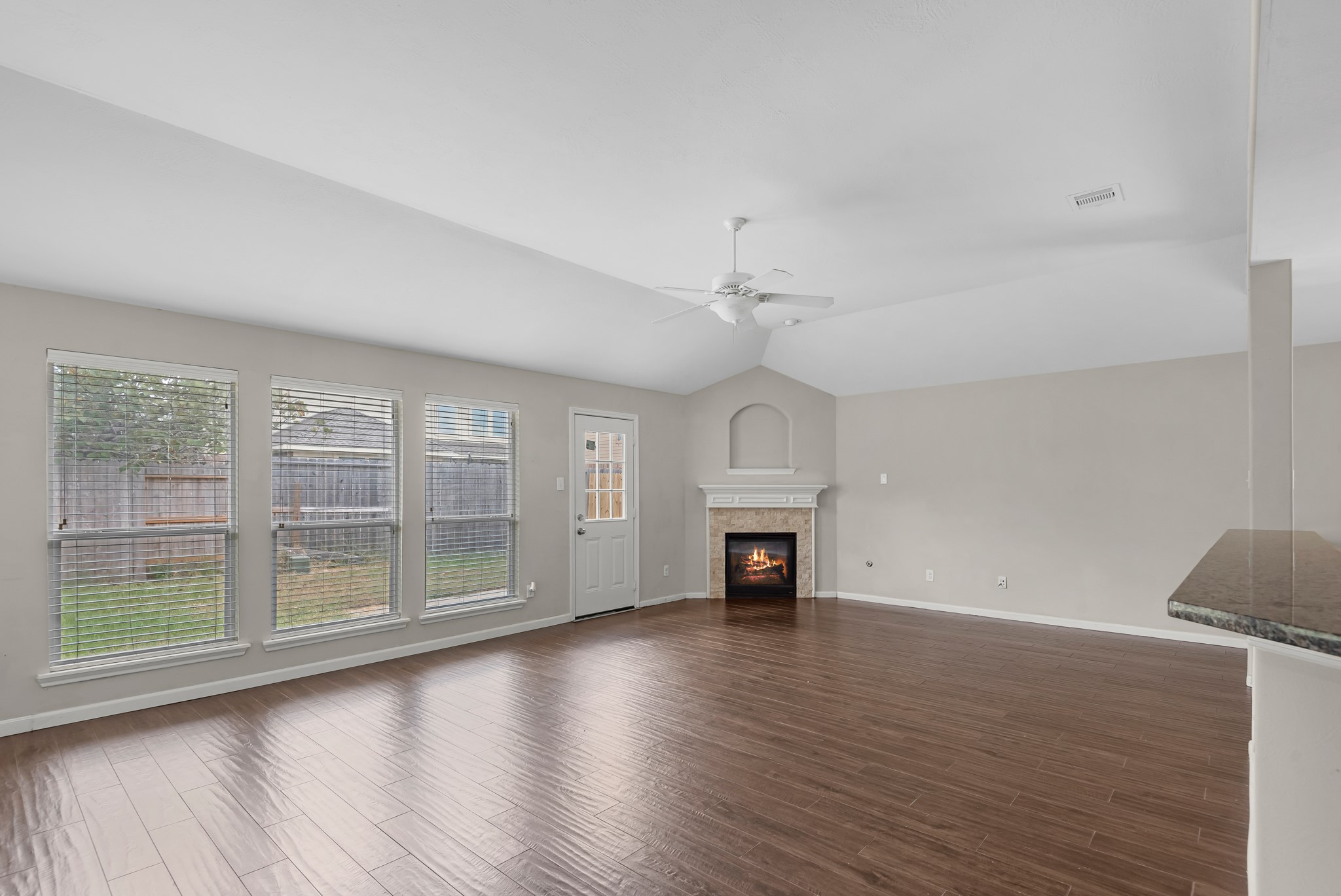 8514 Sweetstone Field Court Cypress, TX 77433 - Photo 9 of 23 an empty room with wooden floor fireplace and windows