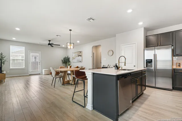 a kitchen with stainless steel appliances granite countertop a table chairs stove and refrigerator