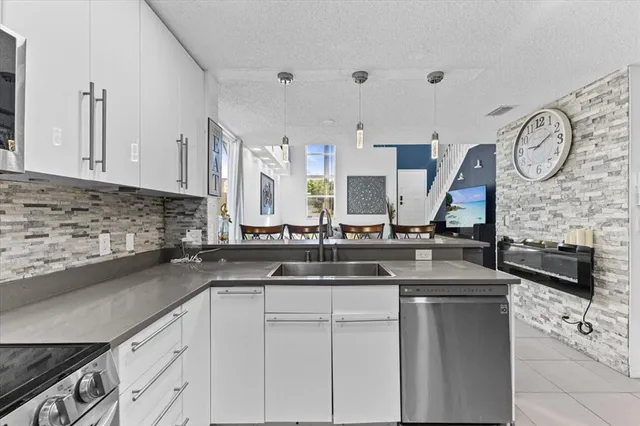a kitchen with stainless steel appliances granite countertop a sink a stove and a wooden cabinets